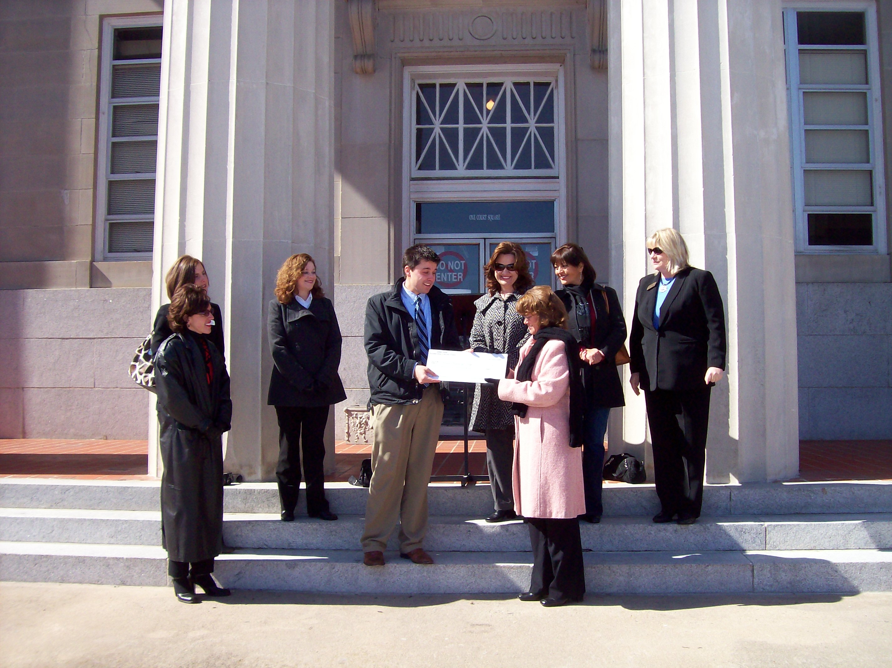 A group presents man with a check on steps